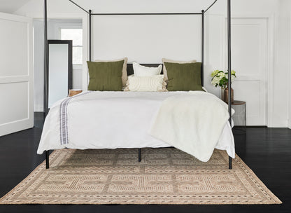 Black four-poster bed with white bedding, olive green & cream pillows, cream throw, geometric natural jute rug.