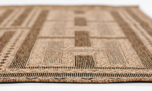 Natural fiber rug with beige and brown geometric patchwork, striped border and braided fringe.