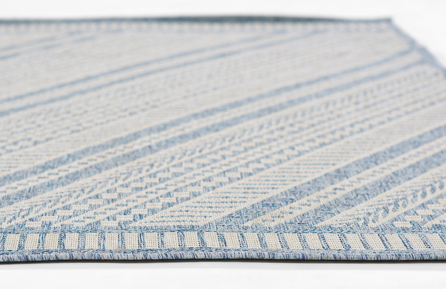 Blue and cream woven rug with geometric stripe patterns and blue fringe along the edge.