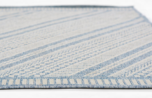 Blue and cream woven rug with geometric stripe patterns and blue fringe along the edge.