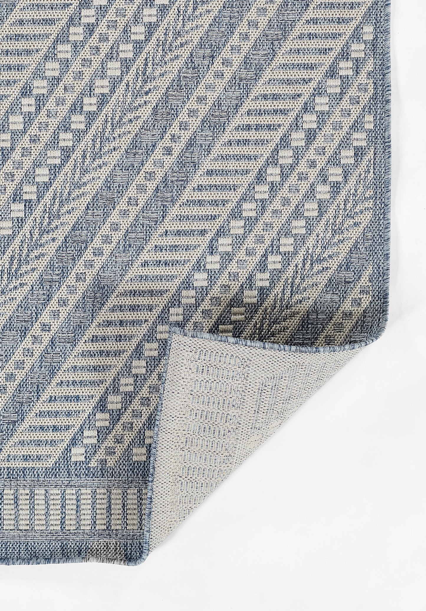 Blue & white geometric woven rug with chevron & diamond stripes; folded corner shows lighter underside.