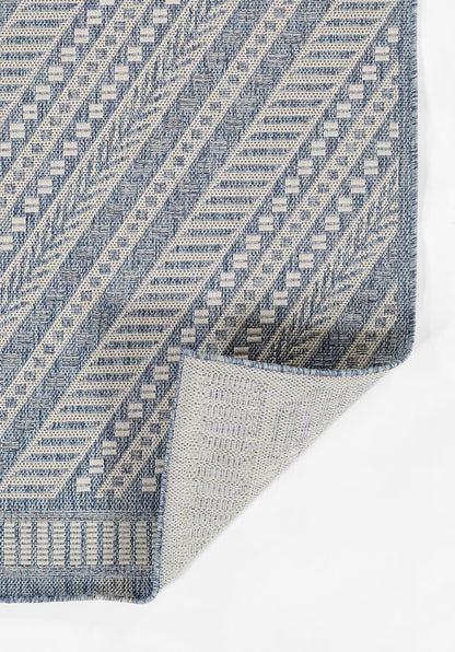 Blue & cream woven rug with geometric diamonds & diagonal stripes; folded corner.
