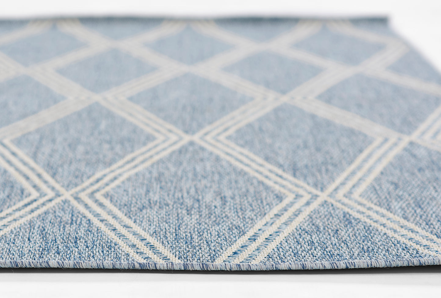 Blue rug with white diamond lattice pattern, denim-like texture, flat-weave style, close-up view