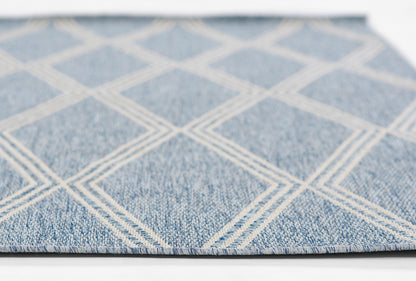 Blue rug with white diamond lattice pattern, denim-like texture, flat-weave style, close-up view