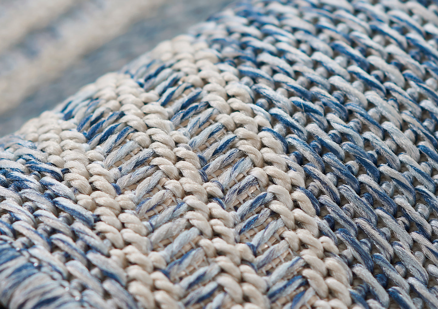 Close-up of a chunky blue and ivory woven rug with braided yarns; rustic nautical style.