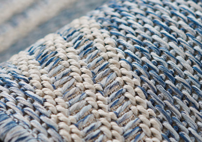 Close-up of a chunky blue and ivory woven rug with braided yarns; rustic nautical style.