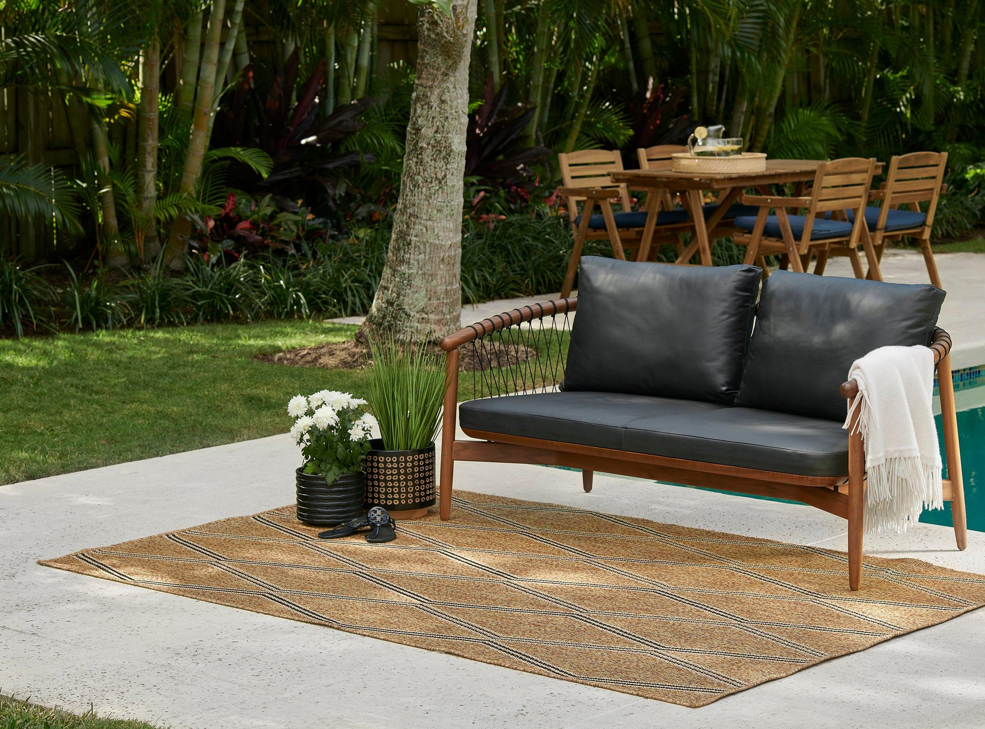 Outdoor natural woven rug runner on a patio, with potted plants nearby.