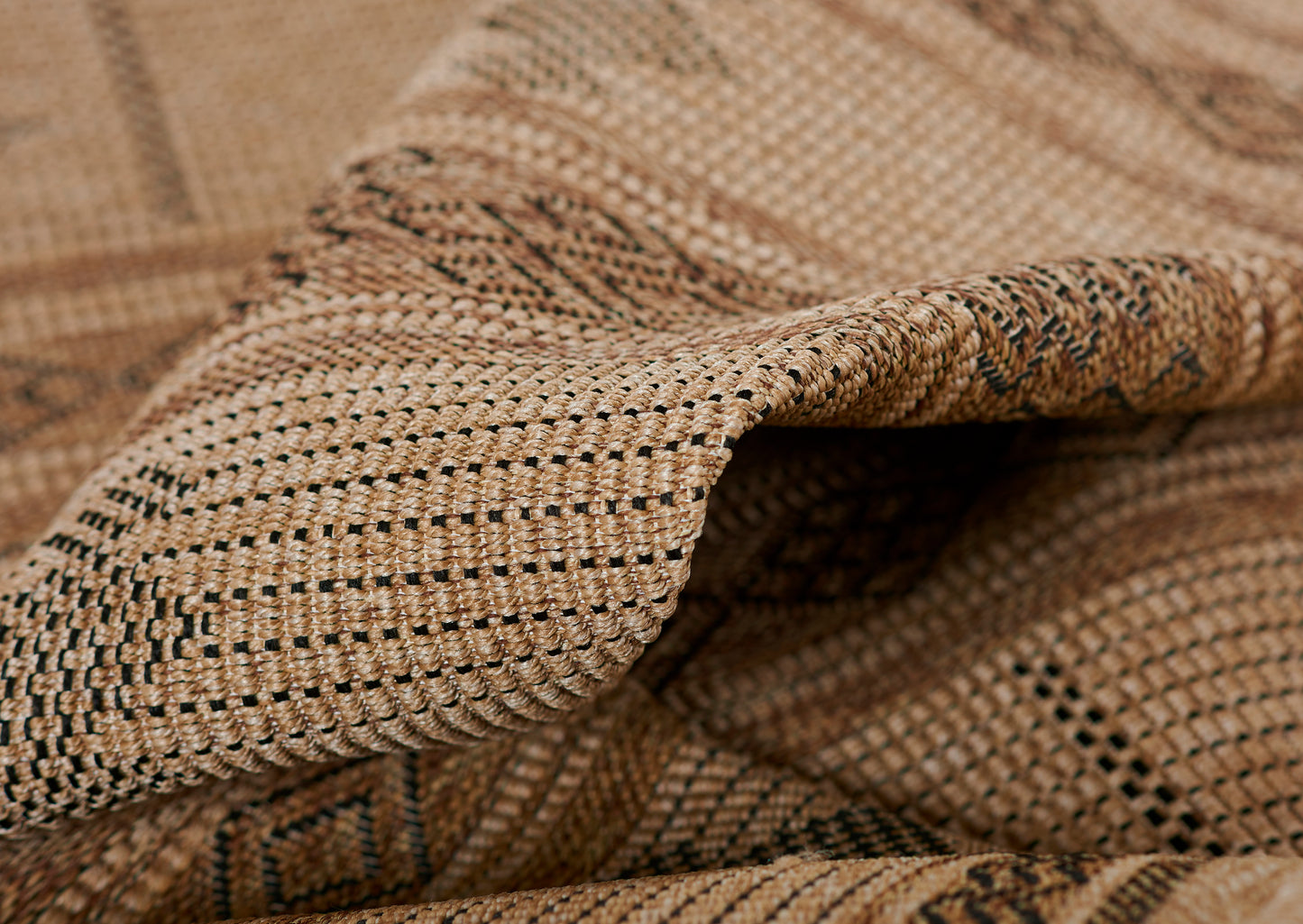 Close-up of natural tan woven raffia rug with a dark speckled pattern; rustic, textured surface.