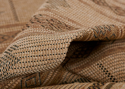 Close-up of natural tan woven raffia rug with a dark speckled pattern; rustic, textured surface.