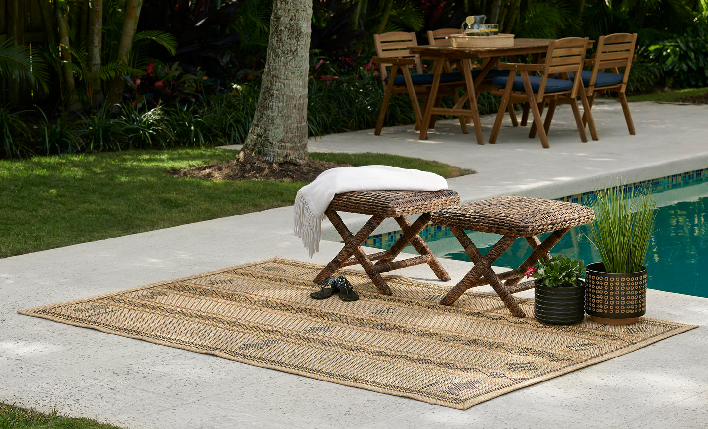 Beige woven outdoor rug, 4' x 6', laid poolside.