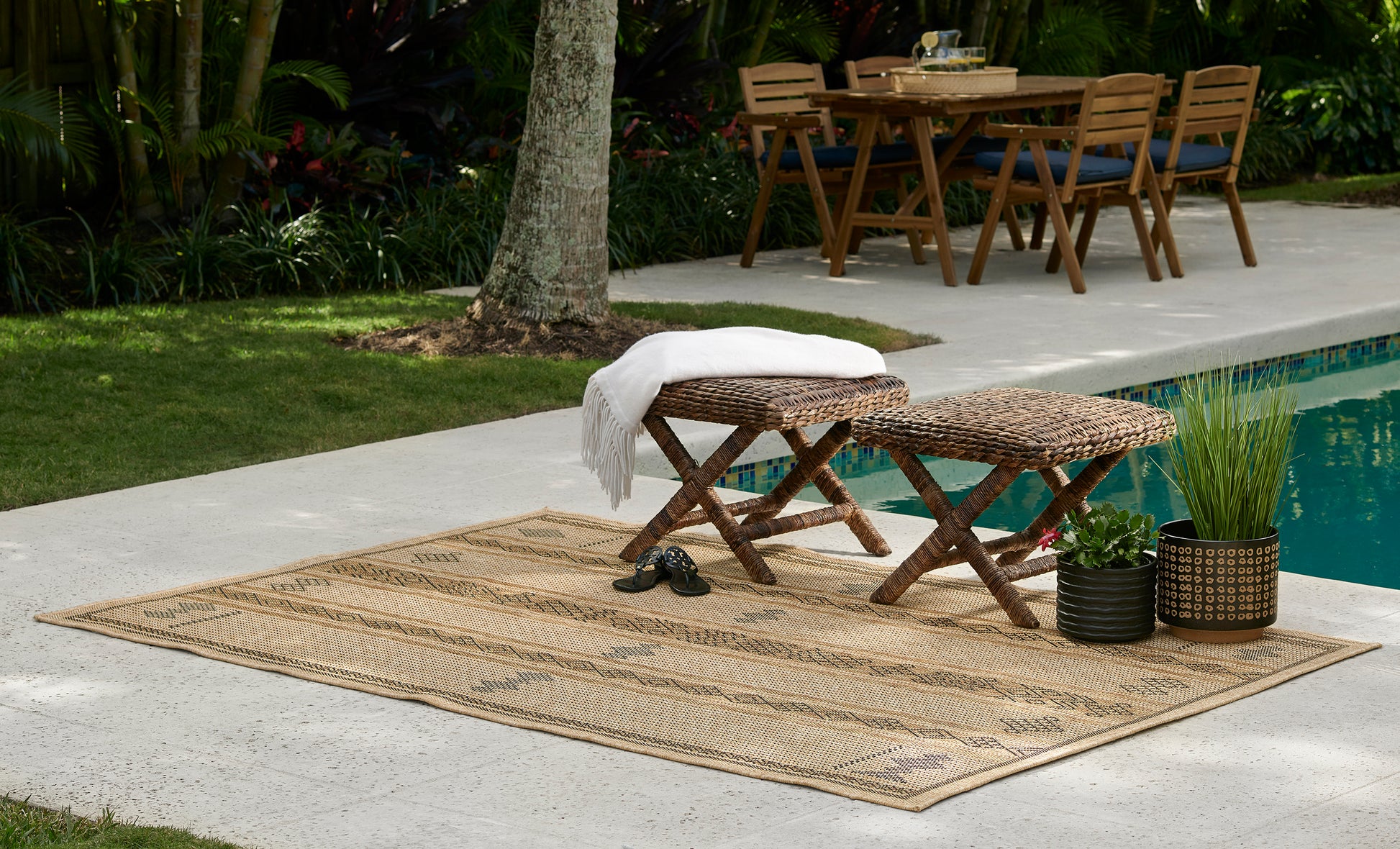 Beige woven outdoor rug, 4' x 6', laid poolside.