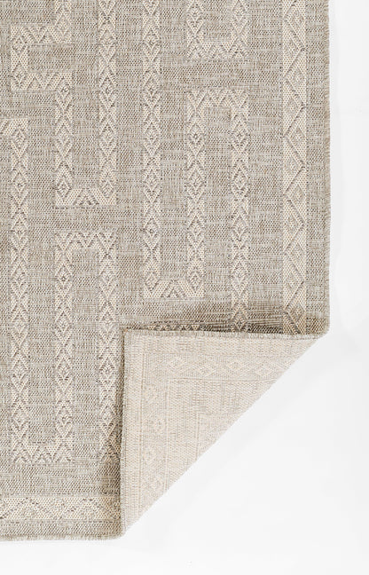 Beige-gray woven rug with geometric diamond pattern and textured border; folded corner reveals thick weave.