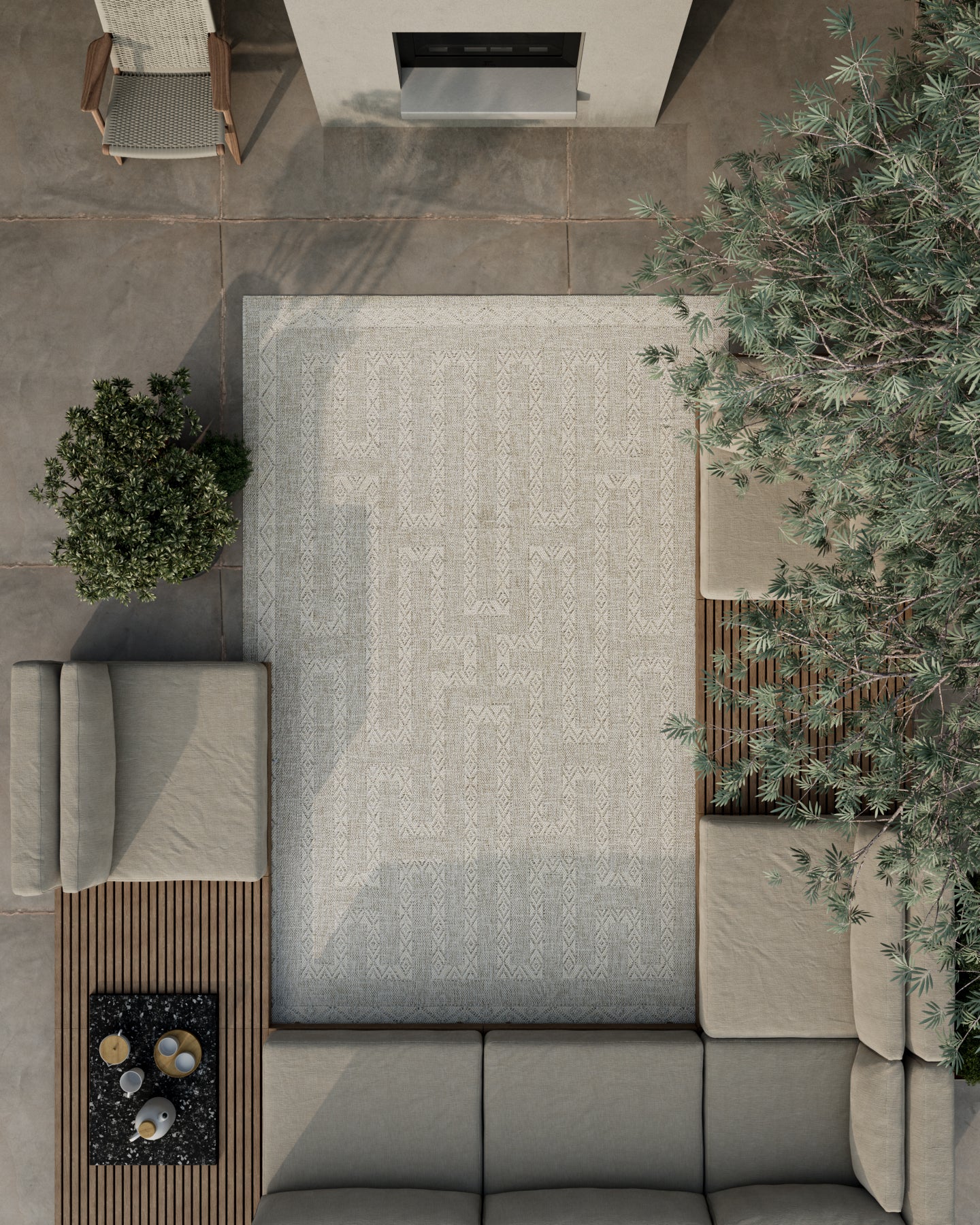 Aerial view of a modern outdoor patio: gray sectional sofa, wooden slat coffee table, large patterned rug, and potted plants.