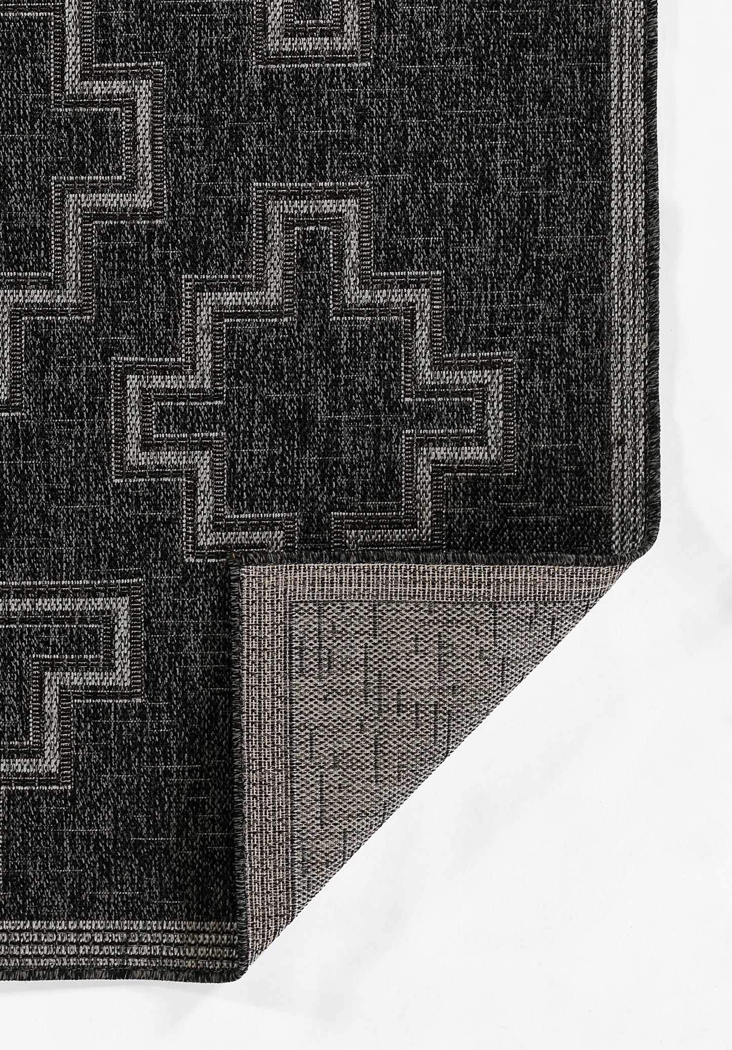 Black geometric area rug with light gray cross motifs; woven texture, folded corner reveals lighter underside.