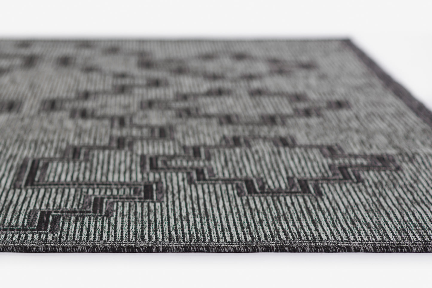 Grey and black geometric rug with a maze-like pattern and woven striped texture, rectangular modern home decor.