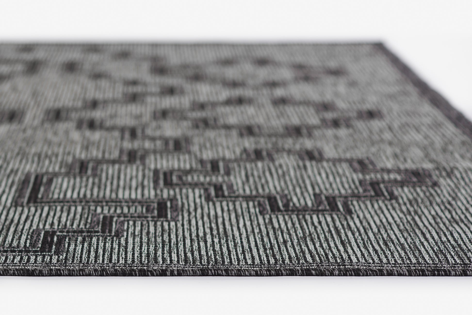Grey and black geometric rug with a maze-like pattern and woven striped texture, rectangular modern home decor.