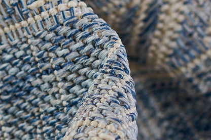 Close-up of blue and cream braided rug texture with a chunky woven pattern.