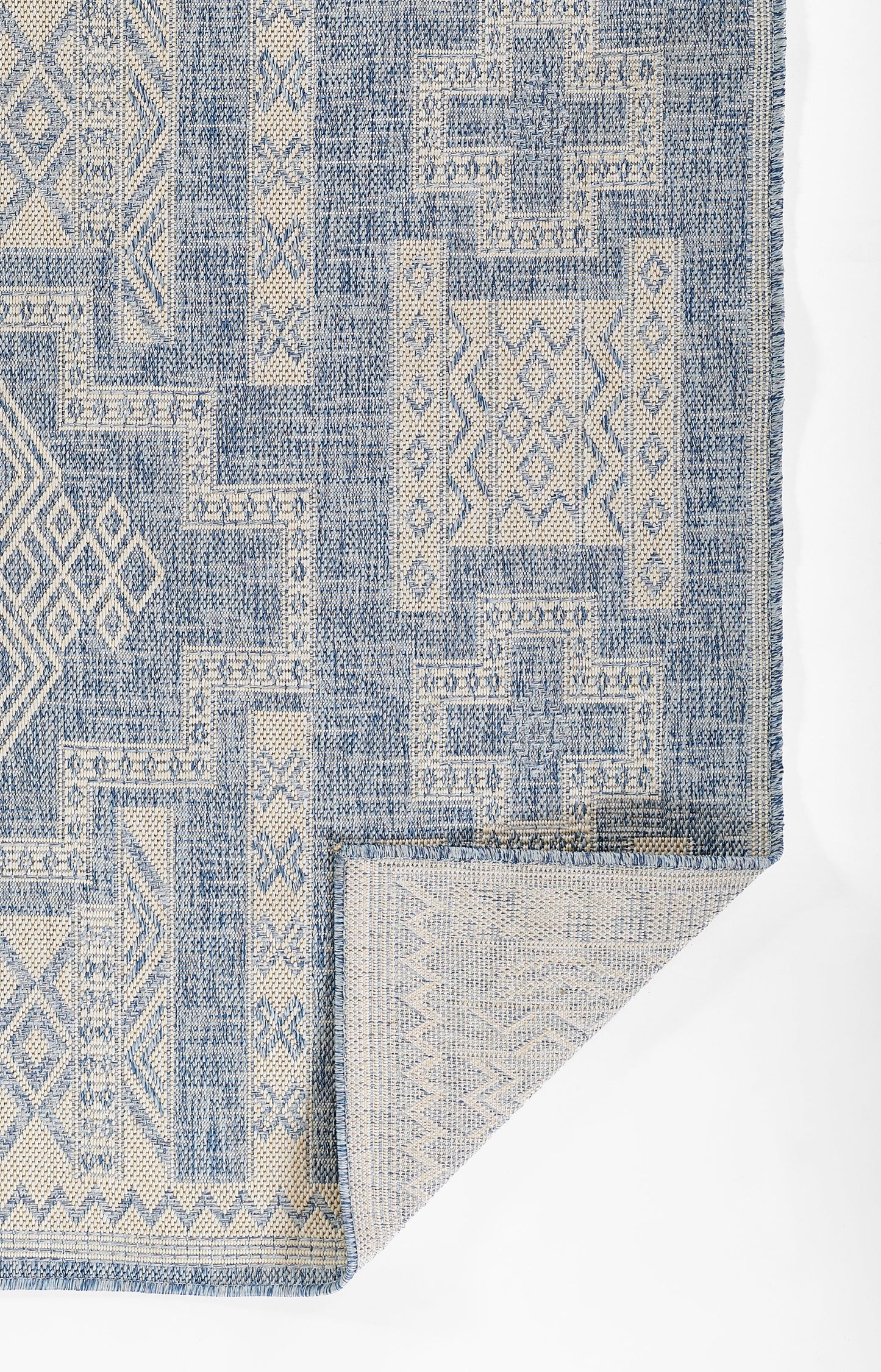 Blue and beige geometric patchwork area rug with woven texture and fringed edges.