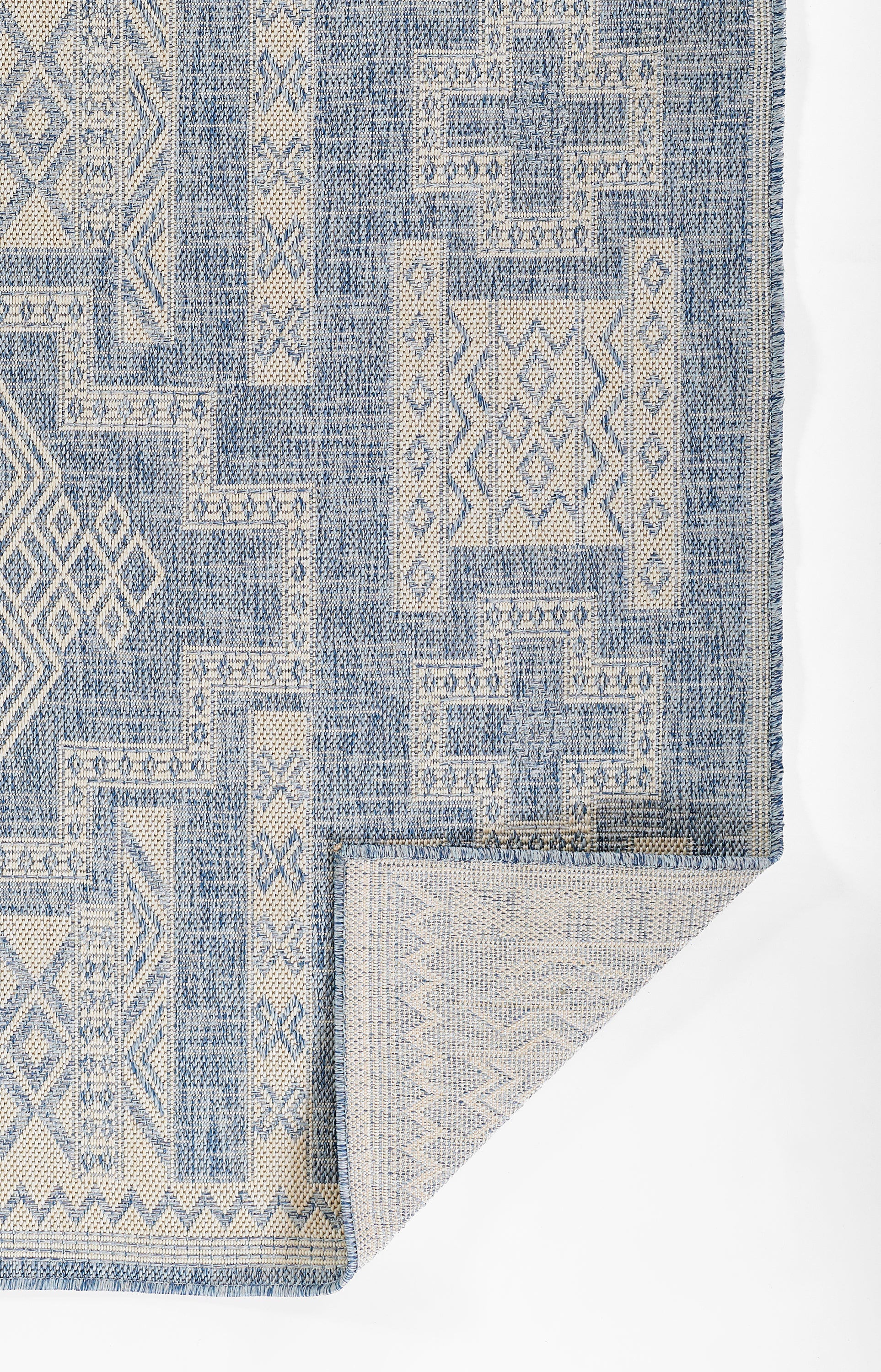 Blue and beige geometric patchwork area rug with woven texture and fringed edges.