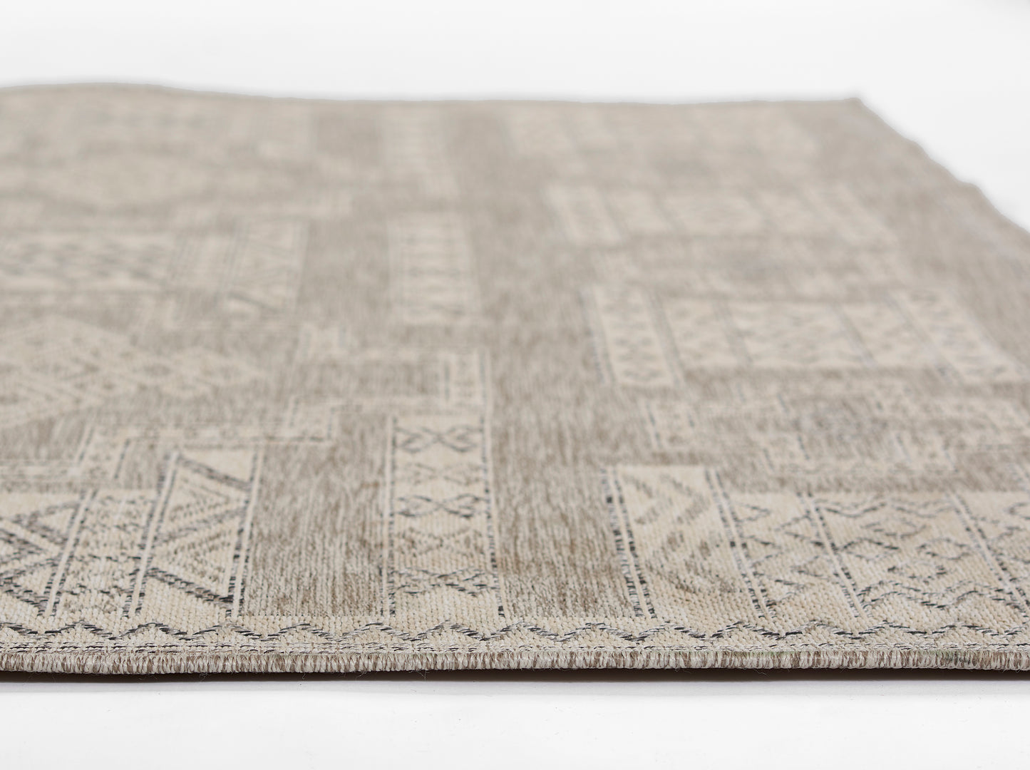 Beige-gray geometric woven area rug with rectangular blocks and zigzag border, close-up view.