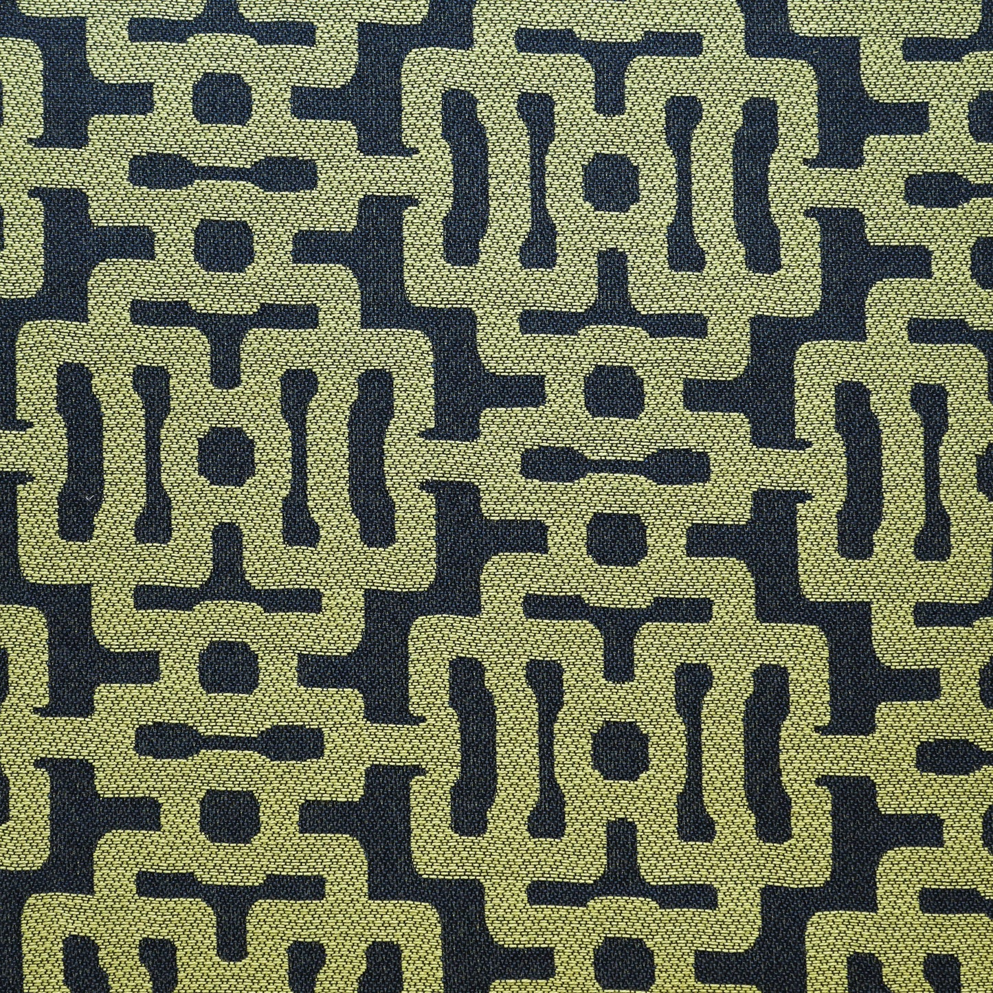 Olive-green geometric lattice on navy; textured woven upholstery fabric in retro mid-century style.