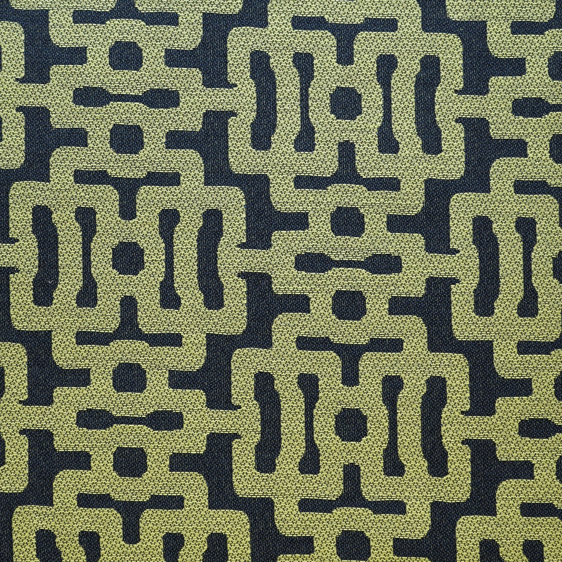 Olive-green geometric lattice on navy; textured woven upholstery fabric in retro mid-century style.