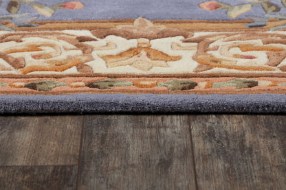 Edge view of a plush rug with purple border and orange, cream, and brown pattern on dark wood floor.