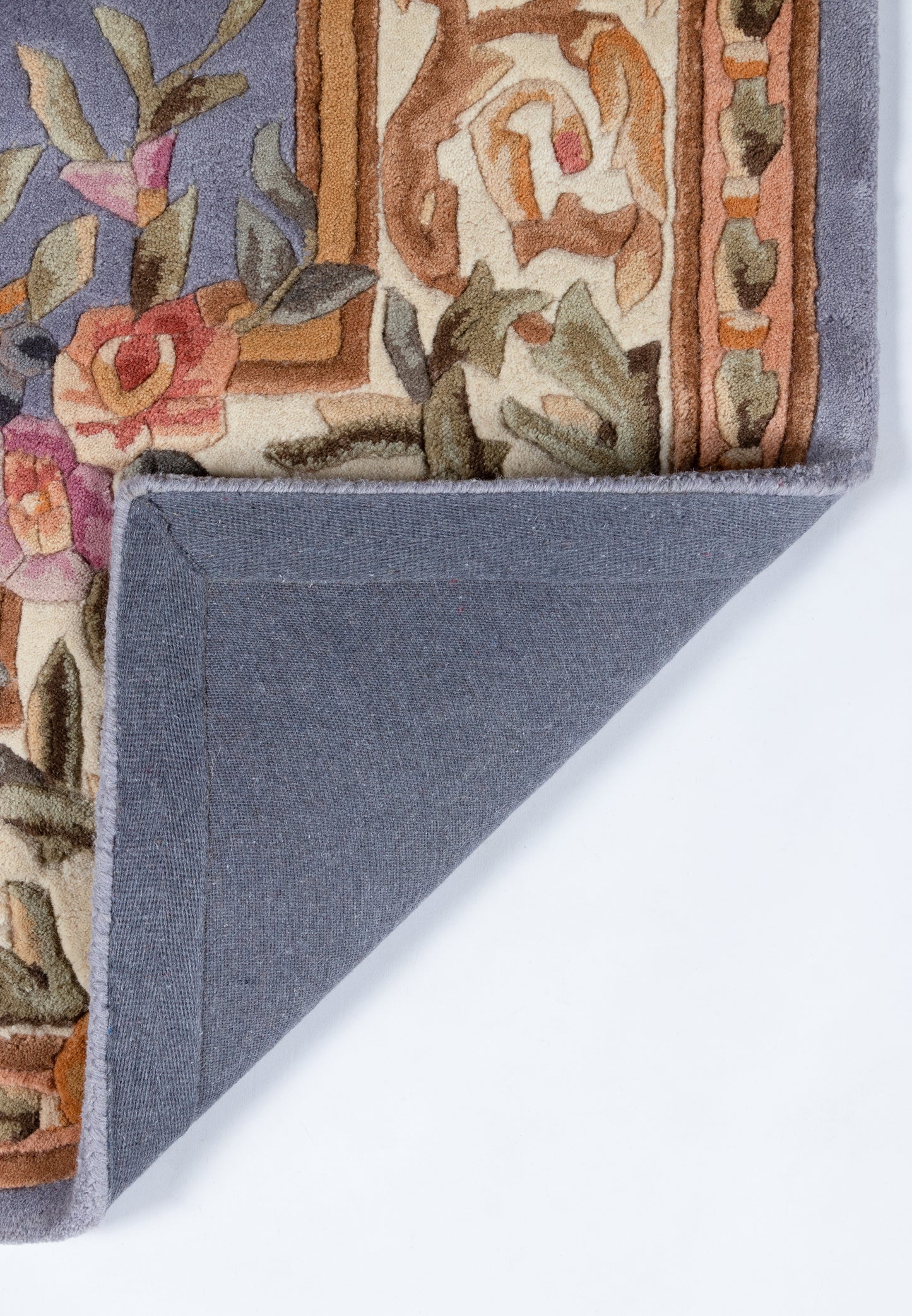 Blue-violet floral area rug with cream & rust border, folded corner reveals solid blue backing.