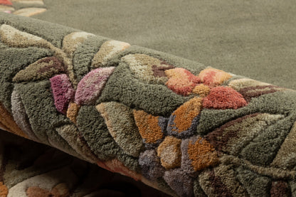 Thick tufted area rug in olive green with multicolor floral shapes in orange, peach and purple; plush pile.