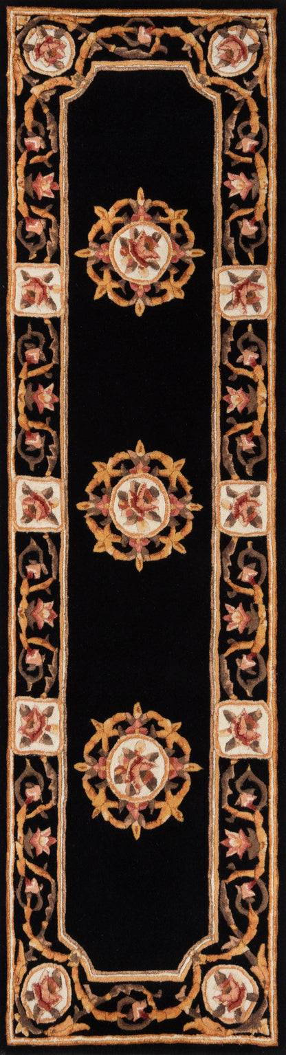 Long black runner rug with ornate gold scroll border, pink floral medallions and small square edge tiles.