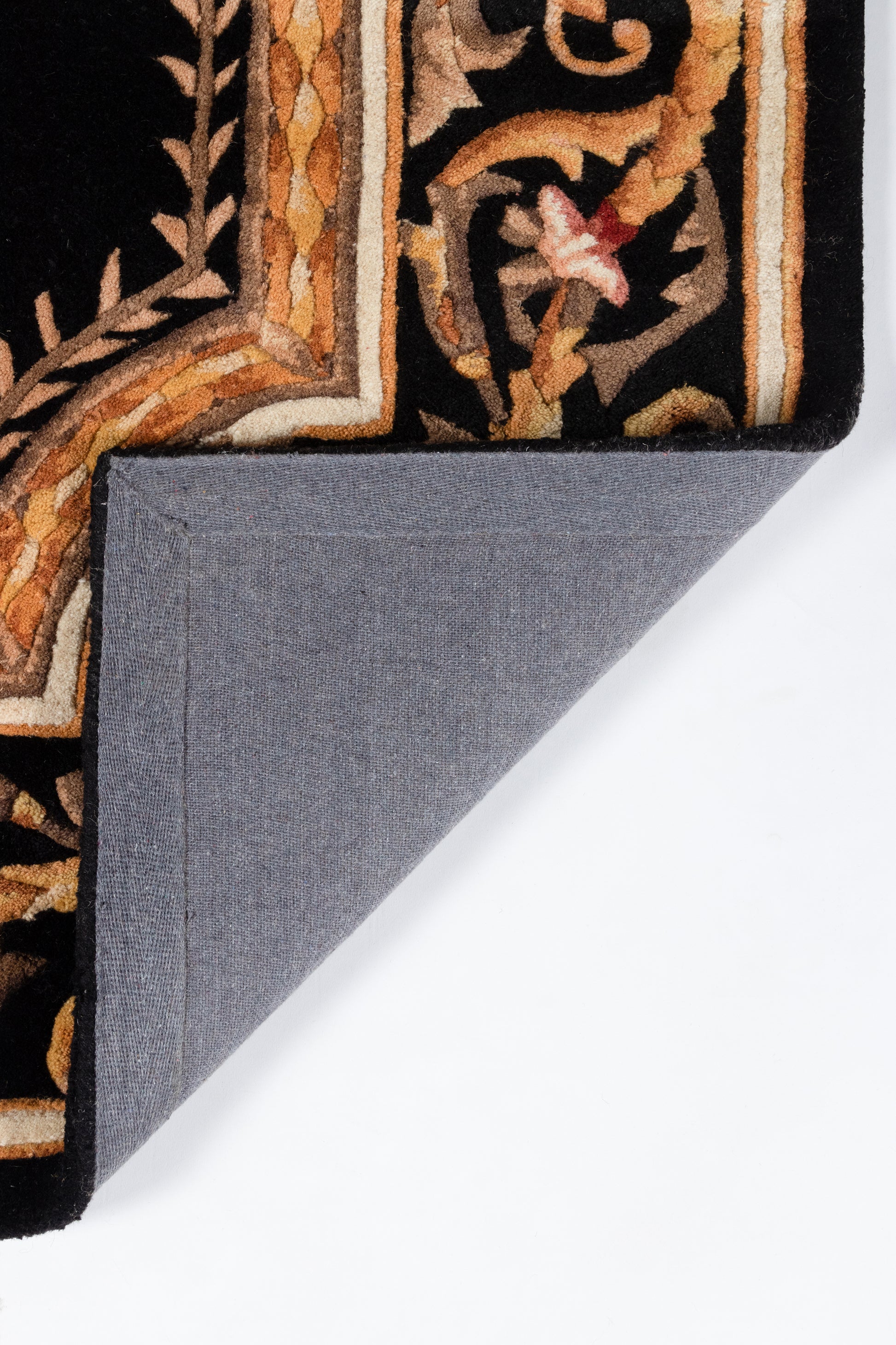 Ornate oriental rug in black, gold and rust with a border motif; blue-gray fabric backing folded over.