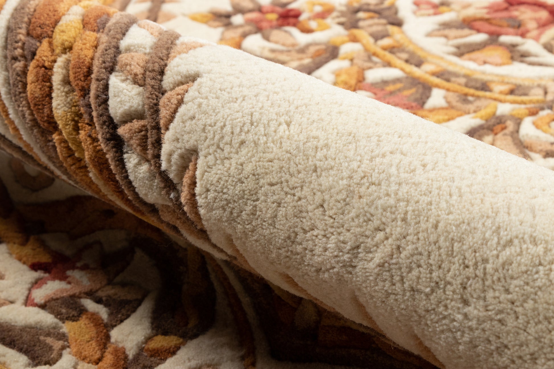 Ivory shag rug with brown, mustard and rust accents; plush pile shown as a rolled sample.