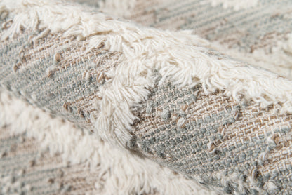 Gray and cream woven rug with fluffy white fringe, textured neutral boho style.