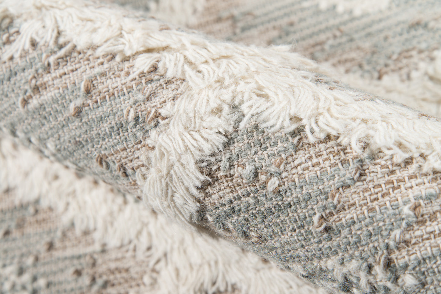 Close-up of a gray and beige woven rug with cream fringe, textured kilim-style surface for cozy living spaces.
