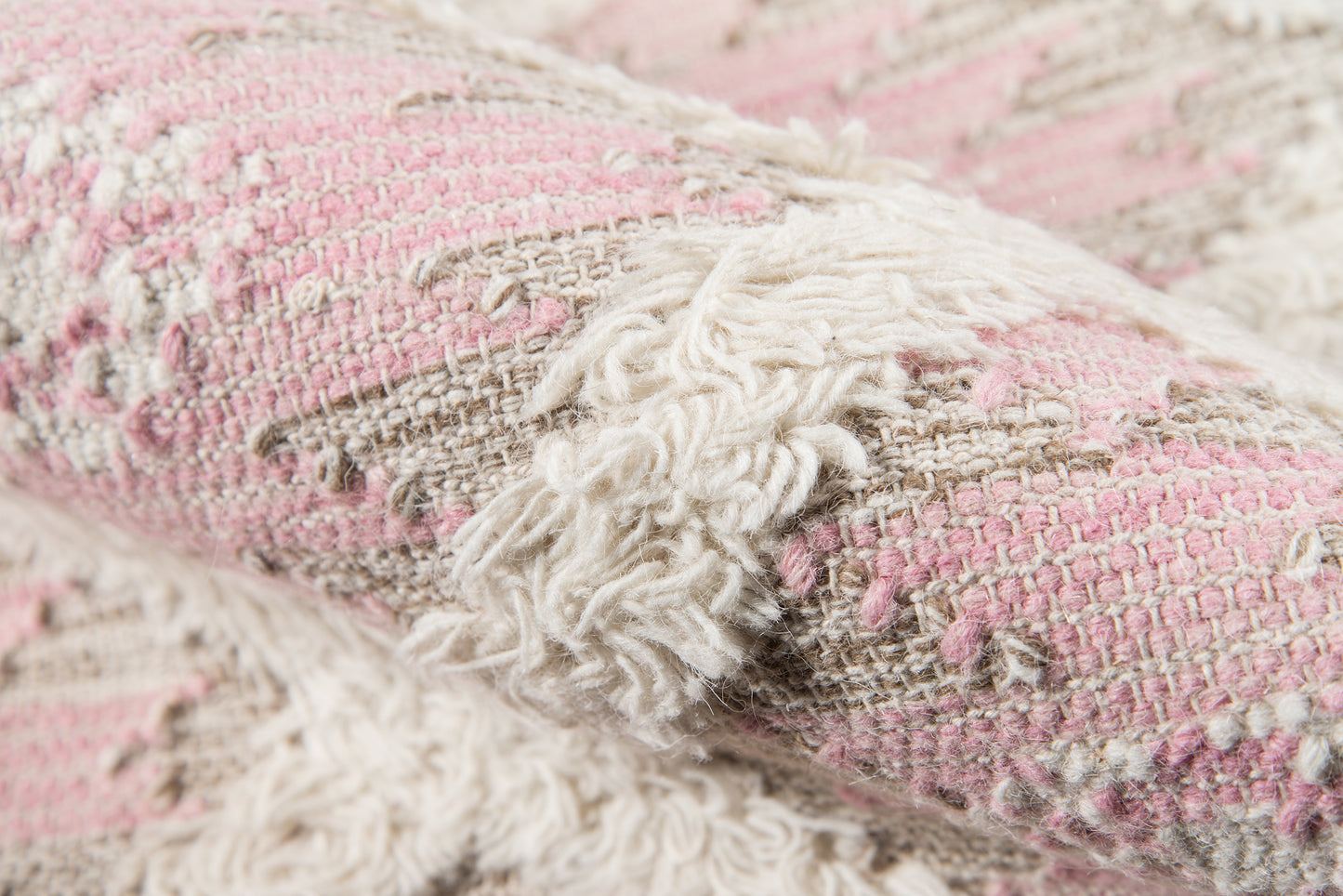 Pink and beige woven rug with fluffy white fringe tassels, textured boho home decor.