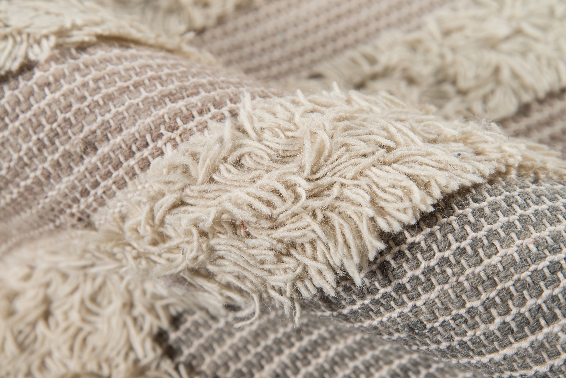 Beige and gray woven rug, 9' x 12', with thick fluffy fringe along the edge.