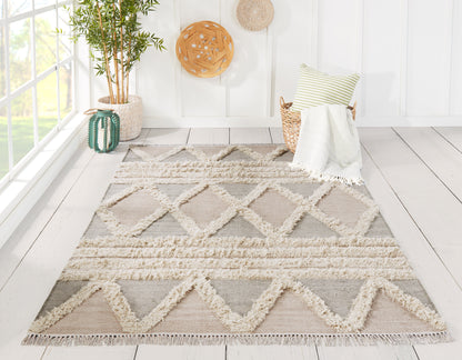 Neutral geometric rug with cream fringe and taupe-gray diamonds in a sunlit wicker-chair living space.