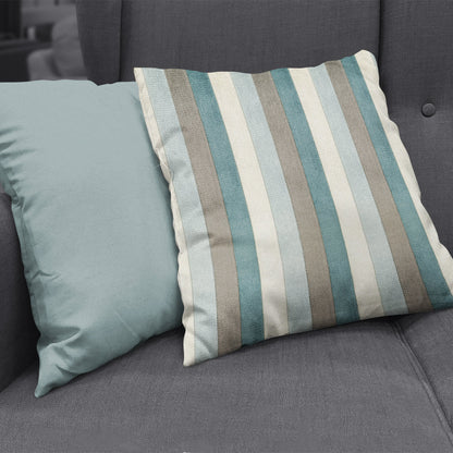 Two throw pillows on a dark gray sofa; one solid teal, the other blue, beige and gray striped.