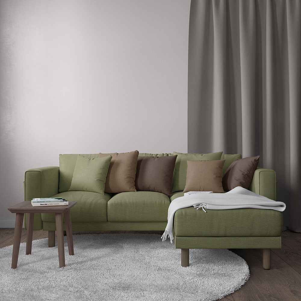 Olive-green fabric sectional sofa with chaise, earth-toned cushions, wooden legs, a small coffee table on a gray rug.