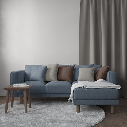 Blue-gray fabric sectional with chaise, multicolor cushions, wooden legs, and gray throw blanket in modern living room.