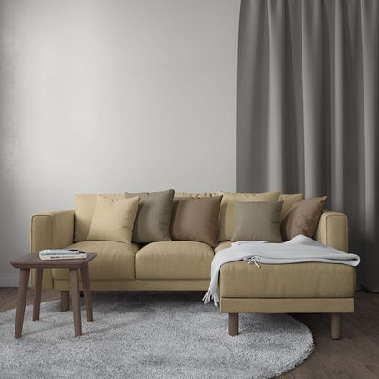 Beige sectional with chaise, neutral cushions, white throw, wooden side table and gray rug.
