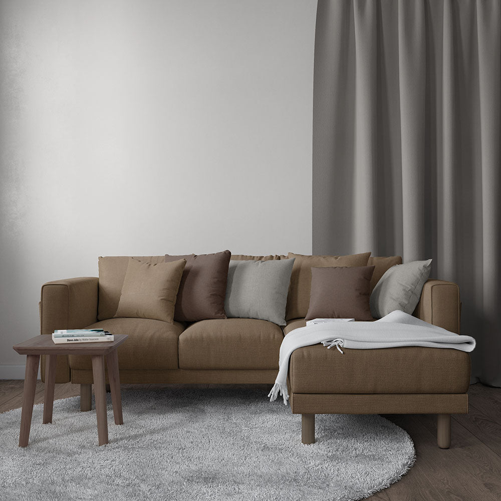 Brown fabric sectional sofa with chaise on right, tan/gray cushions, gray throw blanket, wooden coffee table, gray rug.