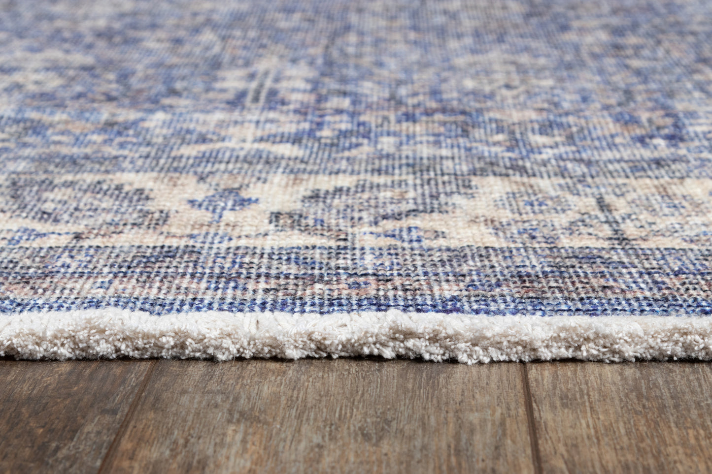 Blue and beige patterned runner rug with cream fringe on a wooden floor.