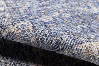 Blue-gray woven runner with beige speckles, textured mottled pattern, rolled edge close-up.