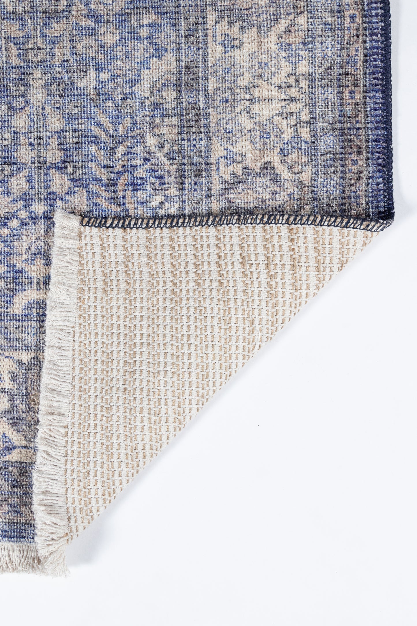 Blue and beige floral oriental rug; Persian-style pattern, folded corner reveals beige woven underside and dark edge.