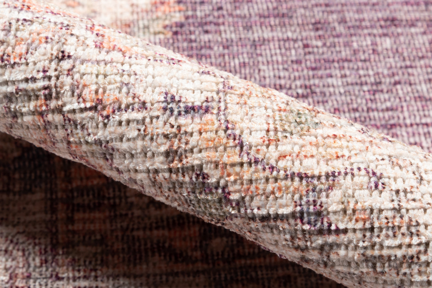 Close-up of a plush beige woven rug with orange, purple and pink threads in a textured plaid pattern.