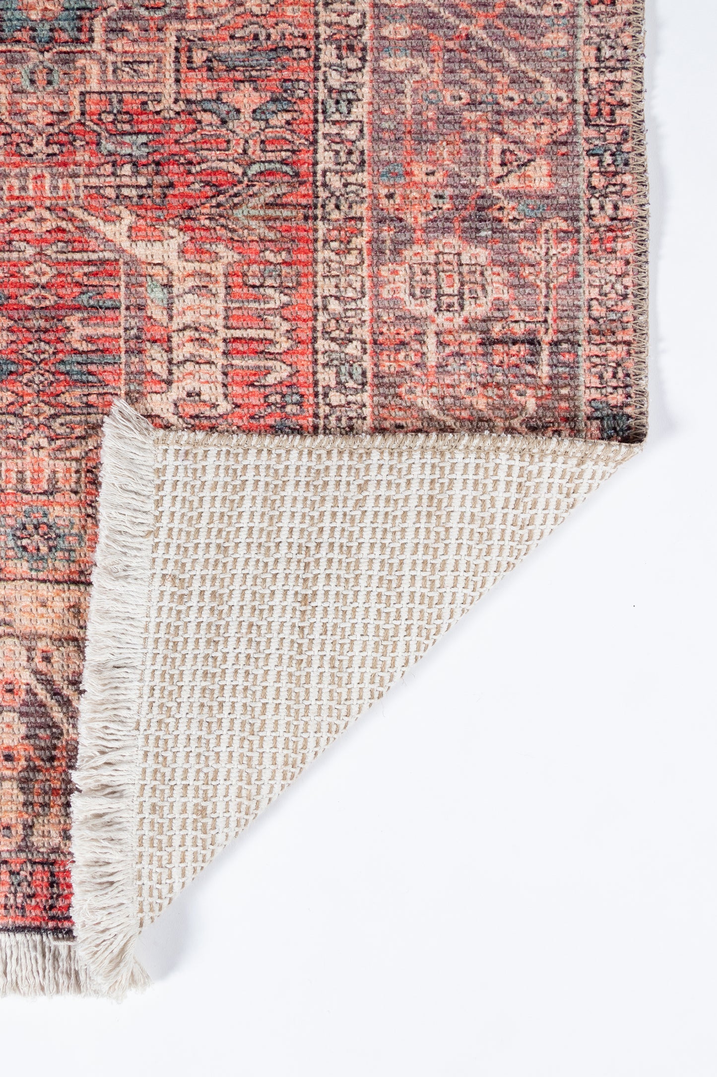 Persian-style runner rug with red, ivory and blue floral motifs; fringed edge, corner folded to reveal beige underside.