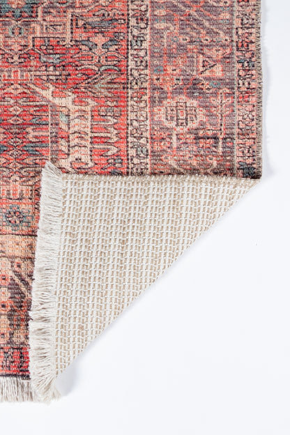 Persian-style runner rug with red, ivory and blue floral motifs; fringed edge, corner folded to reveal beige underside.