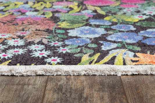 Close-up of a vibrant floral area rug with a dark base, multicolored blossoms, and a cream fringe along the edge.