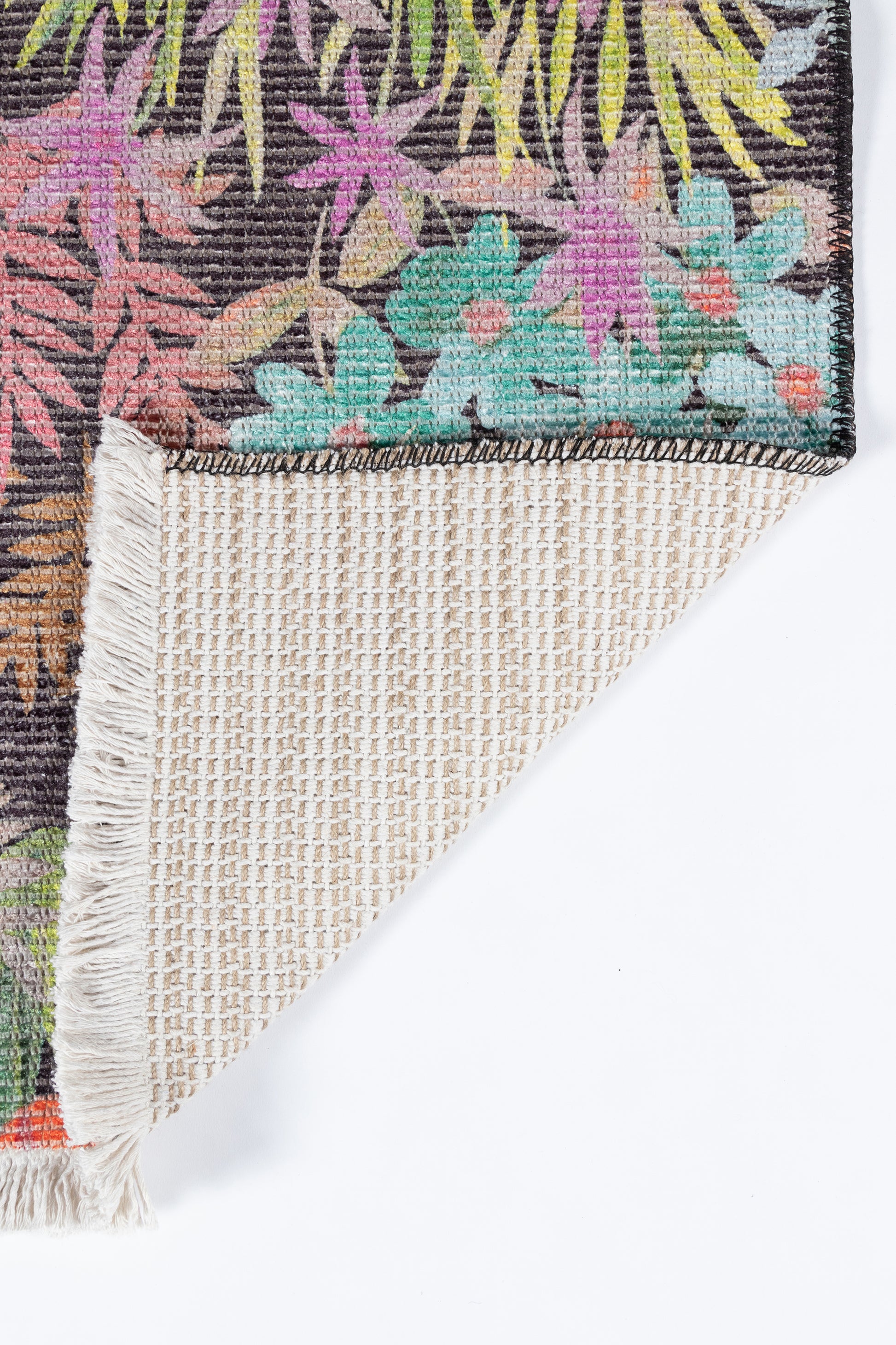 Colorful tropical floral rug with dark background, vibrant pink, green, yellow flowers; fringe edges and beige woven back.